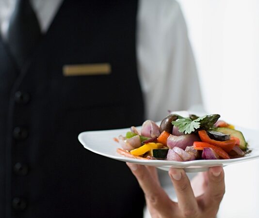 Modern Yemek Kültüründe Servisin Önemi Yemek sadece karın doyurma eylemi değildir, aynı zamanda kültürel bir deneyimdir. Bu deneyimin en önemli parçalarından biri de servis sürecidir. Sofraya getirilen her tabağın düzeni, kullanılan tabak ve çatal-bıçak seçimi, hatta yemeklerin sırasıyla sunulması bile yemeğin nasıl algılandığını etkiler. Özellikle restoranlarda servis, müşteri memnuniyetini belirleyen en kritik unsurlardan biridir. Konulu bir haber görseli.