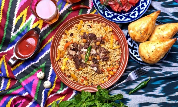 Özbekistan Mutfağı Özbekistan mutfağı, Orta Asya’nın bereketli topraklarında, tarih boyunca farklı kültürlerin etkisiyle şekillenmiş zengin bir gastronomi mirasına sahiptir. İpek Yolu’nun kesişim noktalarından biri olan Özbekistan, hem Doğu hem de Batı mutfak geleneklerini harmanlamış, yemek kültürünü çeşitlendirmiştir. Et ve tahıllar, mutfağın temelini oluştururken; baharatlar ve taze sebzeler, yemeklere özgün tat ve aroma kazandırır. Konulu bir haber görseli.