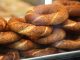 Simit Türk Kültürünün Vazgeçilmez Lezzeti Simit, Osmanlı döneminden günümüze kadar gelen köklü bir geçmişe sahiptir. İlk olarak saray mutfaklarında farklı un karışımlarıyla yapılan bu lezzet, zamanla halk arasında yaygınlaşarak günlük yaşamın bir parçası haline gelmiştir. Özellikle 16. yüzyıldan itibaren İstanbul’da simit fırınlarının açılmasıyla birlikte, bu eşsiz yiyecek şehir kültürünün önemli bir unsuru olmuştur.