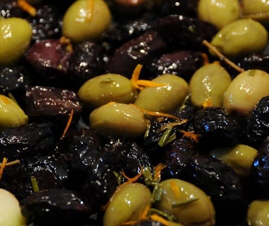 Zeytin, Akdeniz mutfağının en önemli ve en eski besinlerinden biri olarak sofralarda vazgeçilmez bir yer tutar. Hem sofralık olarak hem de zeytinyağı yapımında kullanılan zeytin, çeşitliliğiyle de dikkat çeker. Türkiye’de özellikle Ege, Marmara ve Akdeniz bölgelerinde yetişen birçok zeytin türü bulunur. Sofralarda zeytin çeşitleri, farklı tat ve aromalarıyla hem damak tadını zenginleştirir hem de kültürel bir miras olarak nesilden nesile aktarılır. Konulu bir haber görseli.