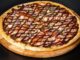 Barbekü pizza, klasik İtalyan pizzalarının modern yorumlarından biri olarak öne çıkar. Barbekü sosu kullanımı, pizzaya özgün bir tat ve aroma katarak farklı bir lezzet deneyimi sunar. İlk olarak Amerika’da ortaya çıkan barbekü pizzası, kısa sürede dünya genelinde popülerlik kazanmıştır. Konulu bir haber görseli.