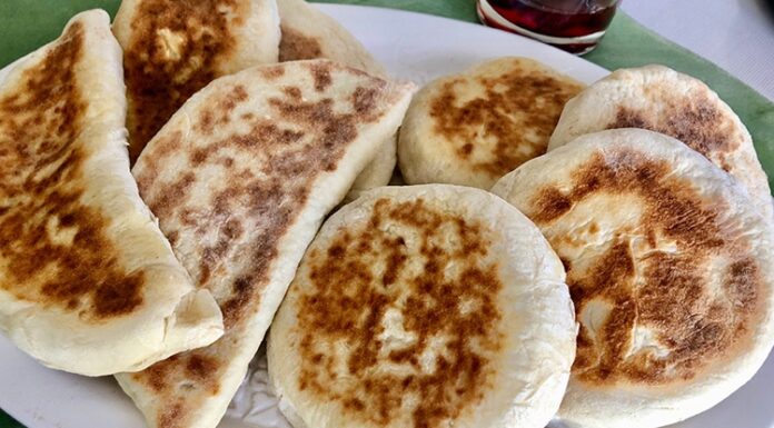 Bazlama: Gelenekten Sofralara Uzanan Sıcak Lezzet Türk mutfağının en özel ve sevilen ekmek çeşitlerinden biri olan bazlama, yumuşak dokusu, doyurucu yapısı ve mis gibi kokusuyla sofraların vazgeçilmezidir. Özellikle Anadolu’nun birçok bölgesinde kahvaltıların, çay saatlerinin ve hatta ana yemeklerin yanında sıklıkla tercih edilen bu ekmek, sadece lezzetiyle değil kültürel bir değer olarak da öne çıkar. Günümüzde modern sofralarda da kendine yer bulan bazlama, hem geleneksel hem de pratik bir lezzet olarak dikkat çekmektedir. Konulu bir haber görseli.