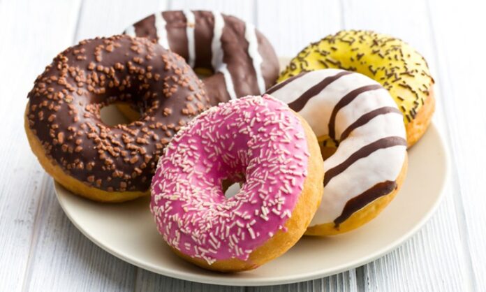 Donut Tatlı Krizlerinin Vazgeçilmez Lezzeti Donut, dünya mutfağının en sevilen hamur işleri arasında yer alır. Adını İngilizce “dough” (hamur) ve “nut” (fındık) kelimelerinin birleşiminden alan bu tatlı, ilk olarak 19. yüzyılda Amerika’da popülerleşmiştir. Başlangıçta sade ve halk arasında basit bir atıştırmalık olarak tüketilen donut, günümüzde çeşitli şekil, dolgu ve kaplamalarla zenginleşmiştir. Konulu bir haber görseli.