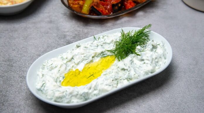 Haydari İle Sofralara Ferahlık Katın Haydari, özellikle kahvaltı sofralarının ve mezelerin vazgeçilmez tatlarından biridir. Yoğurt bazlı bu lezzetli meze, hem hafif hem de besleyici olmasıyla öne çıkar. Haydari, yüksek protein içeriği sayesinde kas ve kemik sağlığını desteklerken, probiyotik özelliği ile sindirim sistemine katkıda bulunur. İçerdiği sarımsak ve dereotu gibi doğal malzemeler, lezzetin yanı sıra sağlık açısından da avantaj sağlar. Konulu bir haber görseli.