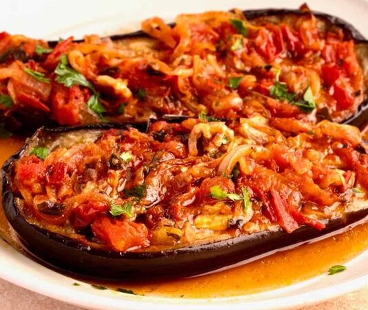 Türk mutfağının klasik zeytinyağlı lezzetlerinden biri olan imam bayıldı, hem hafif hem de besleyici bir yemek olarak bilinir. Osmanlı döneminden günümüze uzanan bu tarif, özellikle patlıcanın közlenmesi ve zeytinyağı ile buluşmasıyla ortaya çıkar. Tarih boyunca hem saray sofralarında hem de halk mutfaklarında hazırlanmış olan imam bayıldı, kültürel bir miras olarak önem taşır. Konulu bir haber görseli.