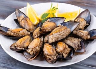 Midye Dolma: Sokakların Vazgeçilmez Lezzeti Türk mutfağının en bilinen sokak lezzetlerinden biri olan midye dolma, kökeni Osmanlı dönemine kadar uzanan köklü bir geçmişe sahiptir. Saray mutfağında farklı baharatlarla hazırlanan pirinçli yemeklerin deniz ürünleriyle birleşmesi sonucu ortaya çıktığı düşünülmektedir. Zamanla bu lezzet, sokaklara taşınarak herkesin ulaşabileceği bir hale gelmiştir. Konulu bir haber görseli.