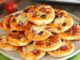 Mini Pizza: Küçük Boyutla Büyük Lezzet Mini pizza, adından da anlaşılacağı üzere standart pizzalardan daha küçük boyutlarda sunulan, özellikle aperatif veya atıştırmalık olarak tercih edilen bir pizza türüdür. Bu pizza türü, küçük porsiyonları sayesinde hem çocuklar hem de hızlı bir atıştırmalık arayan yetişkinler arasında oldukça popüler hale gelmiştir. Konulu bir haber görseli.