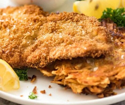 Schnitzel: Klasik Alman Lezzetinin Tarihi ve Evde Hazırlama İpuçları Schnitzel, Almanya ve Avusturya mutfaklarının en bilinen yemeklerinden biridir. İnce dilimlenmiş etin pane harcıyla kaplanıp kızartılmasıyla elde edilen bu lezzet, hem sokak yemekleri hem de restoran menülerinde sıklıkla yer alır. İsmi Almanca “dilim” anlamına gelen “Schnitt” kelimesinden türemiştir ve geleneksel olarak dana veya tavuk eti kullanılır. Konulu bir haber görseli.