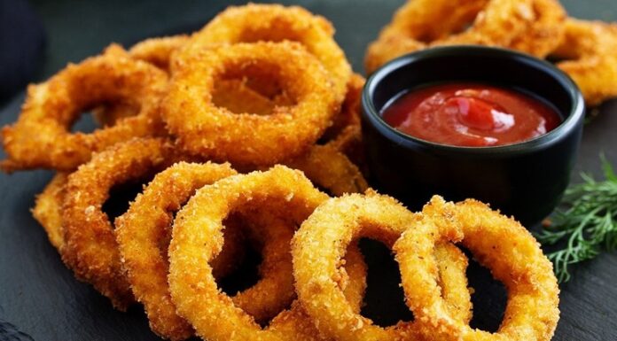 Soğan Halkası: Atıştırmalık Lezzetlerin Vazgeçilmezi Soğan halkası, fast food kültürünün en sevilen atıştırmalıklarından biri olarak öne çıkıyor. Tarihi 20. yüzyılın ortalarına dayanan bu lezzet, özellikle Amerika’da popülerlik kazanmış ve kısa sürede dünya mutfaklarına yayılmıştır. Patates kızartmaları ve burgerlerin yanında ikincil lezzet olarak sunulan soğan halkaları, hem çıtır dokusu hem de tatlımsı soğan aroması ile dikkat çekiyor. Konulu bir haber görseli.