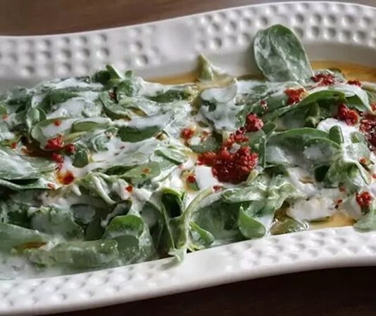 Yoğurtlu semizotu, özellikle yaz aylarında sofraların vazgeçilmez mezelerinden biridir ve hem hafifliği hem de besleyici özelliği ile öne çıkar. Yoğurtlu semizotu, taze semizotu, yoğurt, sarımsak ve zeytinyağı ile hazırlanan, ferahlatıcı ve sağlıklı bir mezedir. Semizotu, omega-3 yağ asitleri ve vitamin açısından zengindir, kalp sağlığını destekler ve bağışıklık sistemine katkıda bulunur. Yoğurt ise protein ve probiyotik içerir, sindirim sistemini güçlendirir ve tokluk hissi yaratır. Konulu bir haber görseli.