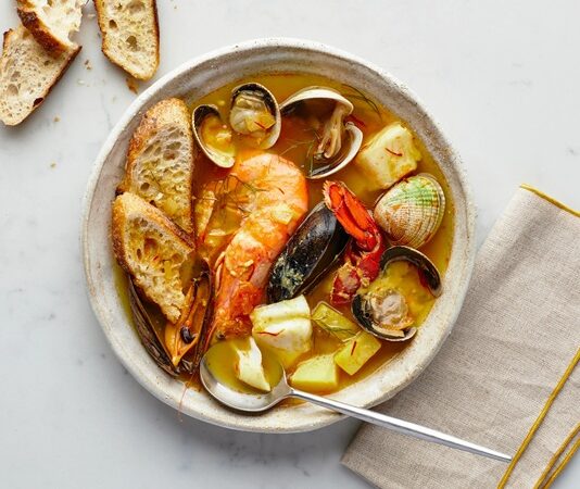 Fransa’nın güney sahillerinde doğan Bouillabaisse, yüzyıllardır Akdeniz mutfak kültürünün en önemli simgelerinden biri olarak biliniyor. Marsilya balıkçıları tarafından geliştirilen bu özel yemek, hem köklü tarihi hem de aromatik yapısıyla son yıllarda yeniden uluslararası arenada büyük bir popülerlik kazandı. Özellikle gastronomi dünyasında artan özgün tarif arayışı, Bouillabaisse gibi geleneksel lezzetleri yeniden öne çıkarıyor. Akdeniz’in karakteristik dokusunu yansıtan çorba, içerdiği taze balıklar, kabuklular ve aromatik sebzelerle hem besleyici hem de kültürel bir değer taşıyor. Konulu bir haber görseli.