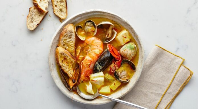 Fransa’nın güney sahillerinde doğan Bouillabaisse, yüzyıllardır Akdeniz mutfak kültürünün en önemli simgelerinden biri olarak biliniyor. Marsilya balıkçıları tarafından geliştirilen bu özel yemek, hem köklü tarihi hem de aromatik yapısıyla son yıllarda yeniden uluslararası arenada büyük bir popülerlik kazandı. Özellikle gastronomi dünyasında artan özgün tarif arayışı, Bouillabaisse gibi geleneksel lezzetleri yeniden öne çıkarıyor. Akdeniz’in karakteristik dokusunu yansıtan çorba, içerdiği taze balıklar, kabuklular ve aromatik sebzelerle hem besleyici hem de kültürel bir değer taşıyor. Konulu bir haber görseli.