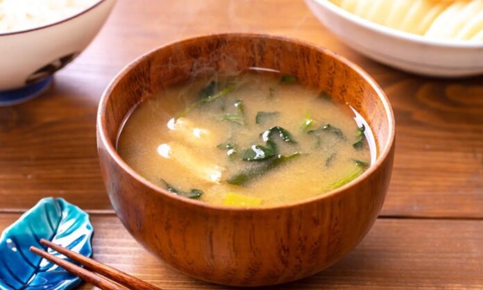 Miso Çorbasının Sırrı Ve Sağlık Üzerindeki Etkileri Miso, Japon mutfağının vazgeçilmez lezzetlerinden biridir ve son yıllarda dünya genelinde sağlıklı beslenme trendleri arasında önemli bir yer kazanmıştır. Miso, fermente edilmiş soya fasulyesi ve tuzdan elde edilen geleneksel bir Japon gıdasıdır. Sade görünmesine rağmen, içerdiği zengin besin değerleri sayesinde hem lezzet hem de sağlık açısından büyük faydalar sunar. Japon kültüründe günlük beslenmenin ayrılmaz bir parçası olan miso, çorba, sos ve hatta bazı tatlı tariflerinde bile kullanılmaktadır. Konulu bir haber görseli.