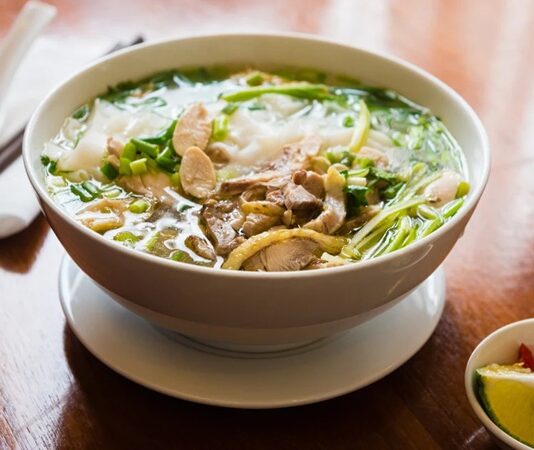 Vietnam mutfağının dünya çapında tanınan ve en çok sevilen yemeklerinden biri olan Pho, hem sokak yemekleri kültürünün hem de gurme restoranların vazgeçilmezlerinden biri hâline gelmiştir. Hafif ama bir o kadar da aromatik yapısıyla öne çıkan bu çorba, özellikle et suyu bazlı tarifleri ve taze baharatlarıyla farklı damak zevklerine hitap eder. Pho, sadece bir çorba değil, aynı zamanda Vietnam’ın tarihini, kültürel dokusunu ve mutfak geleneğini sofralara taşıyan önemli bir gastronomik mirastır. Konulu bir haber görseli.