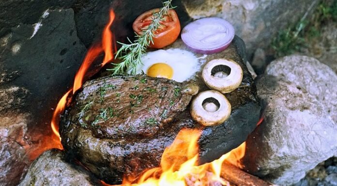 Ateşle Taşın Buluşması Isıtılmış Taş Üzerinde Pişirme Geleneği Yemek pişirme teknikleri, insanlık tarihinin en eski kültürel pratiklerinden biri olarak kabul edilir. Bu teknikler arasında yer alan Isıtılmış Taş Üzerinde Pişirme, doğayla doğrudan temas kuran, ilkel ama bir o kadar da etkili bir yöntem olarak öne çıkar. Ateşle ısıtılan taşların üzerinde ya da taşların yardımıyla yapılan bu pişirme biçimi, hem tarihsel hem de kültürel açıdan güçlü anlamlar taşır. Günümüzde gastronomi dünyasında yeniden ilgi gören bu yöntem, geçmişle bugünü aynı sofrada buluşturur. Konulu bir haber görseli.