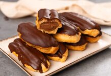 Fransız pastacılığının dünya mutfağına kazandırdığı en özel tatlardan biri olan eclair, yalnızca görünümüyle değil, ince dokusu ve hafif dolgusu ile de tatlı severlerin vazgeçilmezi olarak gösteriliyor. Günümüzde pek çok pastane menüsünde rastladığımız bu tatlı, aslında aristokrat mutfaklarından çıkıp modern mutfaklara taşınan çok katmanlı bir tarihe sahip. Özellikle çikolata kaplaması ve iç dolgusu ile bilinen eclair, Avrupa’da uzun yıllardır tüketilen bir tatlı olmakla birlikte, son yıllarda Türkiye’de de giderek daha fazla tercih edilmeye başladı. Pastacılığın gelişimi ile beraber farklı dolgular, farklı çikolata türleri ve daha çeşitli glazürlerle sunulan bu tatlı, gastronomik açıdan ciddi bir çeşitliliğin de öncüsü haline geldi. Konulu bir haber görseli.