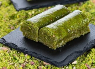 Fıstıklı sarma, Türk tatlı kültürünün hem tarihsel hem damak zevki açısından en özel lezzetlerinden biri olarak biliniyor. Osmanlı saray mutfağından günümüze taşınan zengin mirasın bir parçası olan bu tatlı, özellikle özel günlerde, bayram sofralarında ve davet masalarında sıklıkla tercih ediliyor. Bu nedenle sadece gastronomik bir tatlı olmakla kalmayan fıstıklı sarma, kültürel bir simge haline gelmiş durumda. Şerbetli tatlılar arasında kendine özgü yapısıyla farklı bir yer edinen bu lezzet, hem yapımı hem sunumu hem de ustalığıyla dikkat çekiyor. Konulu bir haber görseli.