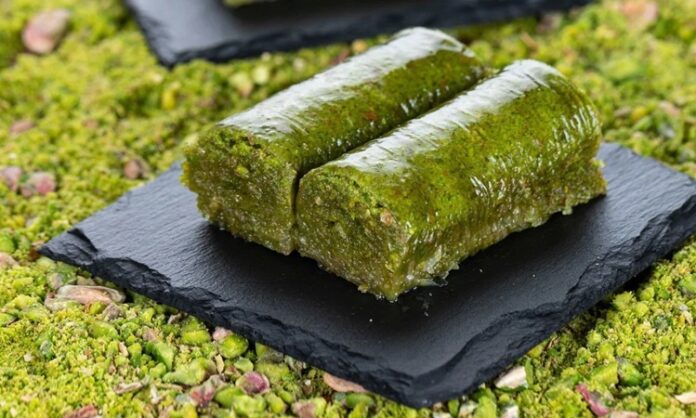 Fıstıklı sarma, Türk tatlı kültürünün hem tarihsel hem damak zevki açısından en özel lezzetlerinden biri olarak biliniyor. Osmanlı saray mutfağından günümüze taşınan zengin mirasın bir parçası olan bu tatlı, özellikle özel günlerde, bayram sofralarında ve davet masalarında sıklıkla tercih ediliyor. Bu nedenle sadece gastronomik bir tatlı olmakla kalmayan fıstıklı sarma, kültürel bir simge haline gelmiş durumda. Şerbetli tatlılar arasında kendine özgü yapısıyla farklı bir yer edinen bu lezzet, hem yapımı hem sunumu hem de ustalığıyla dikkat çekiyor. Konulu bir haber görseli.
