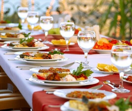 Toplumların en eski ve en canlı ritüellerinden biri olan düğünler, yalnızca iki insanın hayatını birleştirdiği törenler değil, aynı zamanda kültürel sürekliliğin ve toplumsal birlikteliğin sahnelendiği özel anlar olarak kabul edilir. Bu törenlerin merkezinde yer alan Düğün Yemeği, paylaşmanın, bereketin ve misafirperverliğin güçlü bir simgesi olarak öne çıkar. Türkiye’de düğün sofraları, yüzyıllardır farklı coğrafyaların, iklimlerin ve geleneklerin etkisiyle zenginleşmiş; her bölgede kendine özgü bir kimlik kazanmıştır. Konulu bir haber görseli.