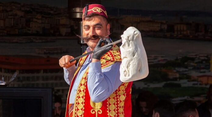 Türkiye’nin gastronomi mirası içinde kendine özgü yapısı, üretim tekniği ve kültürel arka planıyla öne çıkan Maraş dondurması, yalnızca bir tatlı değil aynı zamanda köklü bir geleneğin günümüze taşınmış hâli olarak kabul ediliyor. Özellikle yaz aylarında yoğun ilgi gören bu eşsiz lezzet, dayanıklı yapısı, bıçakla kesilebilen kıvamı ve kendine has aromasıyla klasik dondurmalardan ayrılıyor. Kahramanmaraş ile özdeşleşen bu ürün, bugün hem yerel ekonominin hem de Türkiye’nin tanıtım yüzlerinden biri hâline gelmiş durumda. Konulu bir haber görseli.