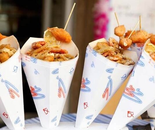 Sokak yemekleri standları, şehir yaşamının en canlı ve en erişilebilir gastronomi alanlarından biri olarak kabul ediliyor. Günün her saatinde farklı kesimlerden insanları bir araya getiren bu alanlar, yalnızca hızlı ve uygun fiyatlı yiyecekler sunmakla kalmıyor, aynı zamanda kentin kültürel dokusunu da yansıtıyor. Sokak yemekleri, geçmişten bugüne hem ekonomik hem de sosyal yönleriyle önemli bir yer tutarken, günümüzde gastronomi turizminin de vazgeçilmez parçalarından biri hâline gelmiş durumda. Konulu bir haber görseli.