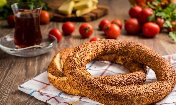 Türkiye’de sokak lezzetleri denildiğinde akla gelen ilk tatlar arasında simit ve açma yer alır. Günün her saatinde ulaşılabilen bu iki hamur işi, yalnızca pratik bir atıştırmalık olmanın ötesinde, şehir yaşamının ritmini belirleyen önemli unsurlardan biri olarak görülür. Sabah işe yetişmeye çalışan bir memurun elinde, okul yolunda koşan bir öğrencinin çantasında ya da sahil kenarında çay eşliğinde tüketilen bu lezzetler, toplumsal hafızanın da güçlü bir parçasıdır. Konulu bir haber görseli.